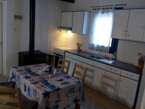 uma cozinha com mesa e cadeiras e uma cozinha com armários brancos em Villa Glaykos em Thymonia Beach