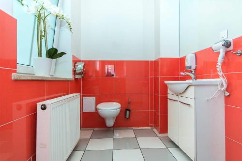 a red bathroom with a toilet and a sink at 3 City Hostel in Gdańsk