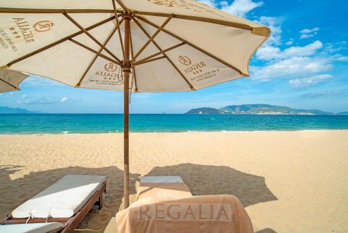 a beach with an umbrella and chairs on the beach at Regalia Nha Trang in Nha Trang