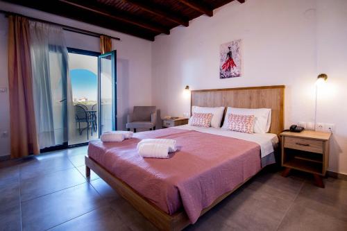a bedroom with a large bed and a balcony at Geranion Village in Nikiti