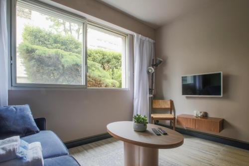 un salon avec un canapé, une table et une fenêtre dans l'établissement Joie Paris GARE MONTPARNASSE, à Paris