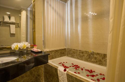 a bathroom with a tub and a sink with flowers on the floor at Huong Sen Hotel in Ho Chi Minh City