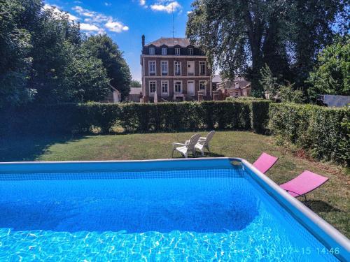a swimming pool in front of a large house at Fief des 3 Guillaume Chambres d'hôtes in Écouis