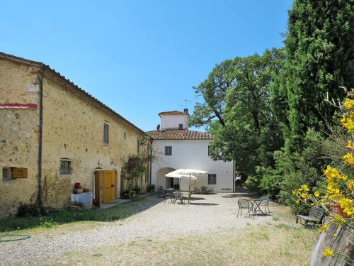 a building with tables and an umbrella in a yard at Agriturismo La Moraia in Poggibonsi