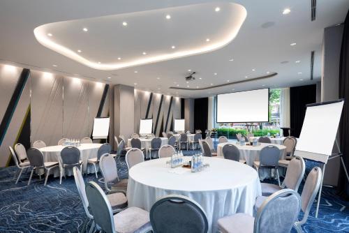 a conference room with tables and chairs and a projection screen at ibis Styles Bangkok Ratchada in Bangkok