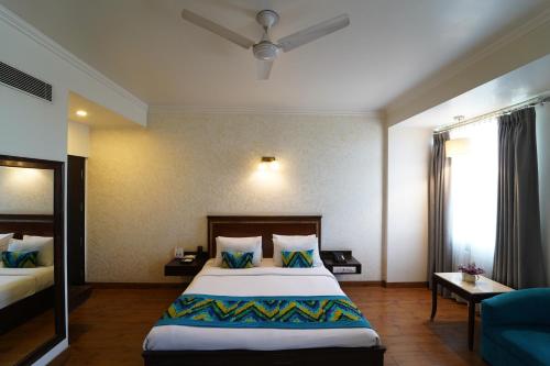 Habitación de hotel con cama y sofá azul en Rockland Hotel, C.R Park, en Nueva Delhi