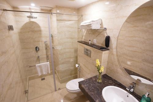 y baño con ducha, aseo y lavamanos. en Rockland Hotel, C.R Park, en Nueva Delhi
