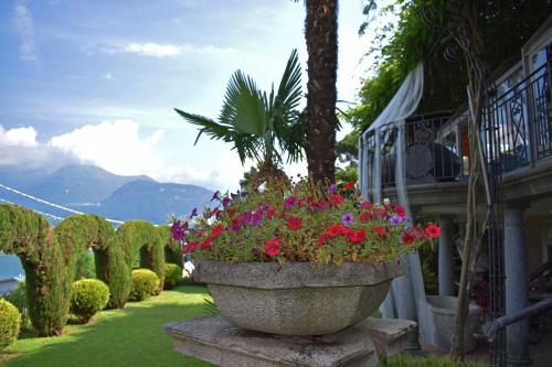 a large stone planter filled with flowers next to a building at Albergo Ristorante Conca Azzurra in Colico