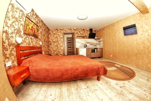 a bedroom with a large orange bed and a kitchen at Комфортні апартаменти в Чернігові in Chernihiv