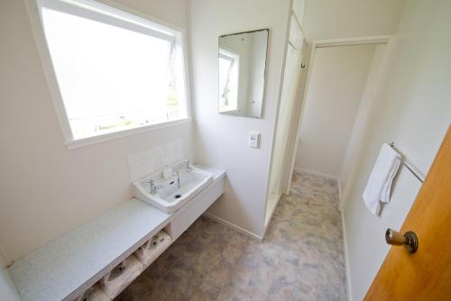 a white bathroom with a sink and a window at Tower Road Motel in Matamata