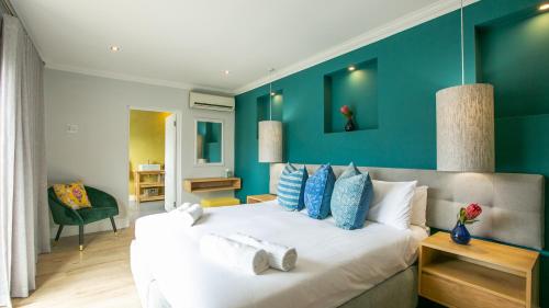 a bedroom with a large white bed with blue walls at Hout & About Guest House in Hout Bay