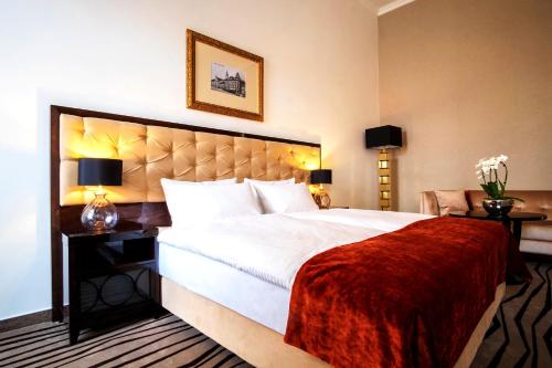 a bedroom with a large white bed with a red blanket at Boutique Hotel Slávia in Košice