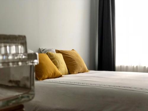 a bed with two yellow pillows and a window at La Terrasse des bords du Cher in Saint-Aignan