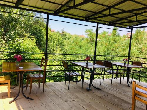 three tables and chairs on a deck with trees at Lia's Guest House in Sighnaghi