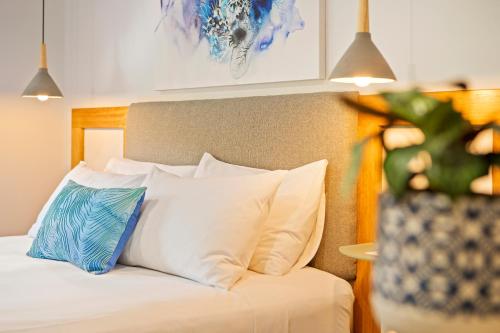 a bed with white pillows and a vase with a plant at Airlie Guest House in Airlie Beach