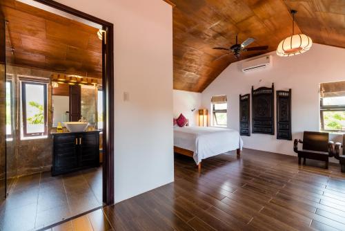 a bedroom with a bed and a bathroom at An Bang Coco Villa in Hoi An