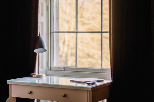 a desk in front of a window with a lamp at Saltmarshe Hall in Saltmarshe
