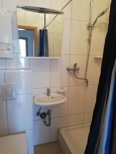 ein Bad mit einem Waschbecken, einem Spiegel und einer Dusche in der Unterkunft Pension da Alessandro in Hemer