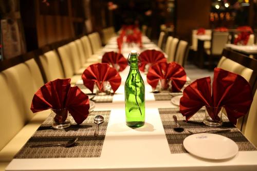 un lungo tavolo con tovaglioli rossi e una bottiglia verde di Hotel Avaante Ahmedabad Formerly known as The Orchid Hotel a Ahmedabad