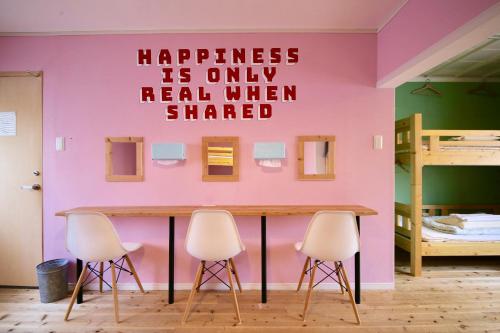 a pink wall with a sign that says happiness is only real when shared at Greenwood Hostel in Izumi-Sano