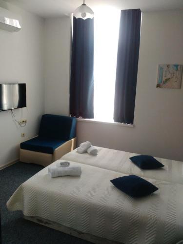 a bedroom with a bed and a chair and a window at Guest House Gurkov in Veliko Tŭrnovo