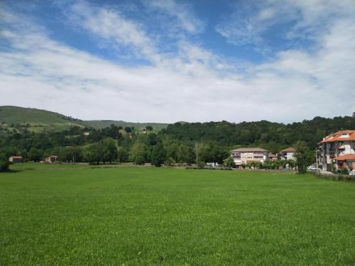 a large green field with houses and mountains in the background at Posada laventa in Selaya