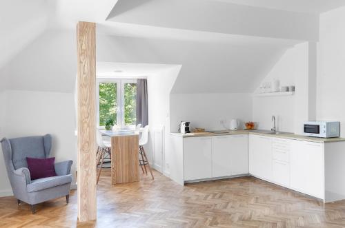 a kitchen with white cabinets and a chair and a table at Opera Apartments in Poznań