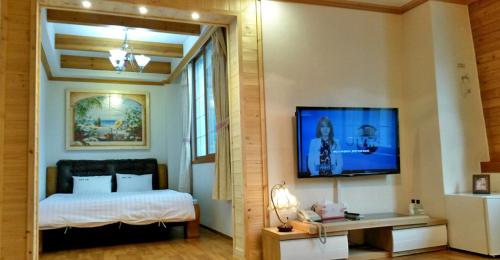 a bedroom with a bed and a flat screen tv at Palgongsan Maeksomseok Youth Hostel in Daegu
