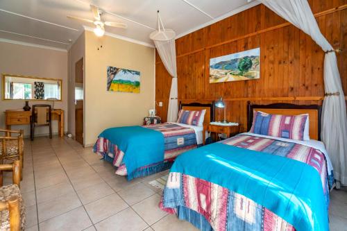 a bedroom with two beds and a table at Old Coach Road Guest House in Barberton