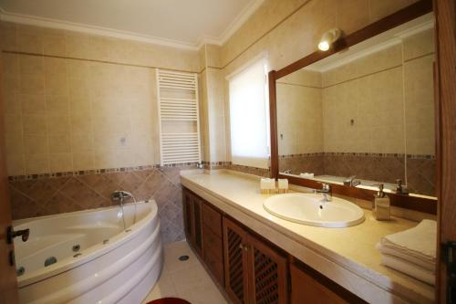 a bathroom with a tub and a sink and a mirror at Paz e Natureza in São Brás de Alportel