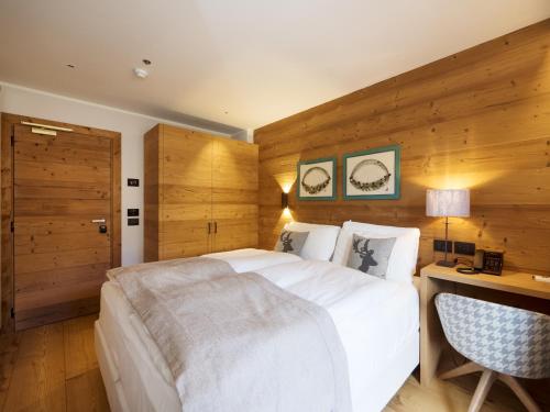 a bedroom with a large white bed and a desk at FIORI Dolomites Experience Hotel in San Vito di Cadore