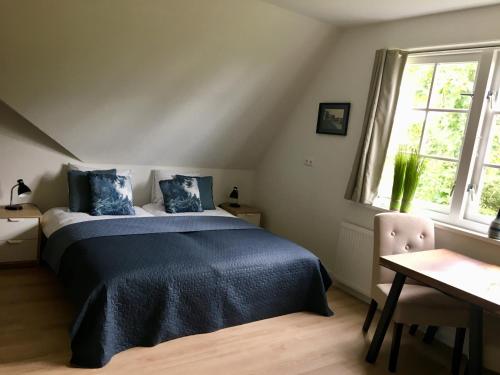 a bedroom with a bed and a table and window at Landhuis Mariëtta in De Koog