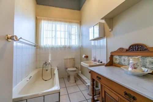 a bathroom with a tub and a toilet and a sink at Old Coach Road Guest House in Barberton