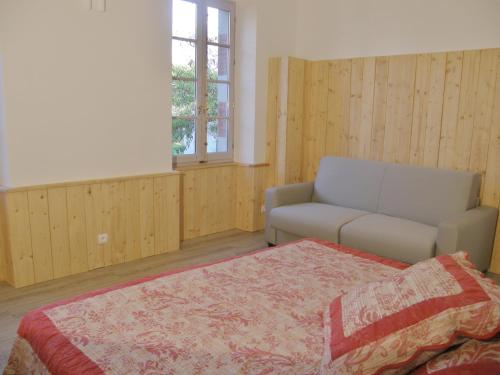 a bedroom with a bed and a couch and a window at Cottage à la Jinolié in Damiatte