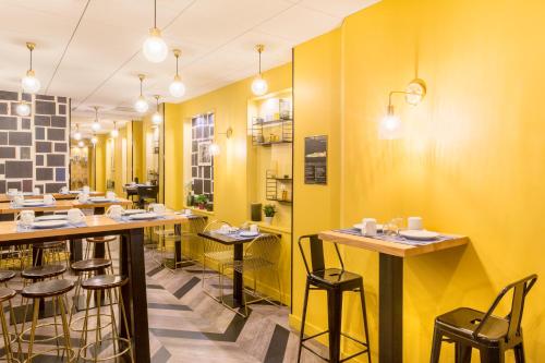 a restaurant with yellow walls and wooden tables and stools at Best Western Hotel Centre Reims in Reims