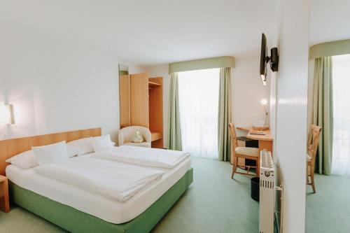 Una habitación de hotel con una cama y un escritorio y una habitación. en Huber's Hotel, en Baden-Baden