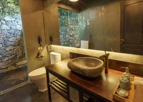 a bathroom with a stone sink on a wooden table at Aravinda Resort Ninh Binh in Ninh Binh