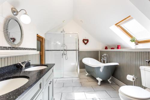 a bathroom with a tub and a sink and a toilet at Red Doors Farm Cottages in Honiton