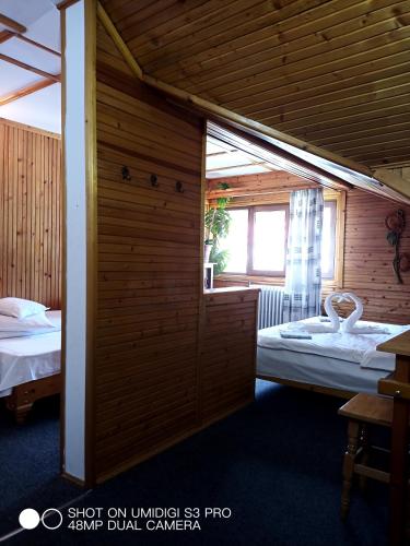 a room with two beds and a wooden wall at Casa Rodica str. Clabucetului 28 in Buşteni