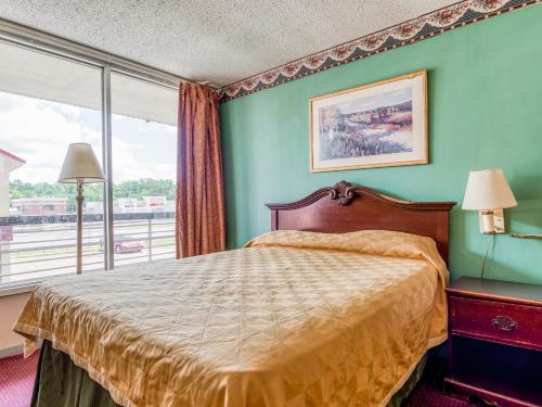 a bedroom with a bed and a large window at OYO Hotel Jackson North I-55 in Jackson