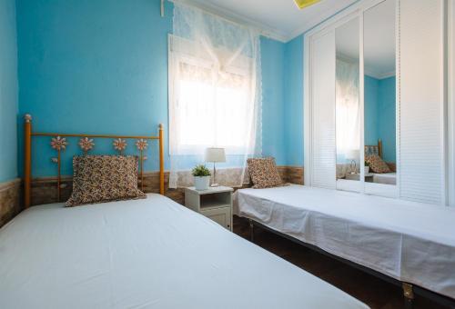 a blue bedroom with two beds and a mirror at Villa Oasis Los Naranjos con jacuzzi 15 min Sevilla in Almensilla