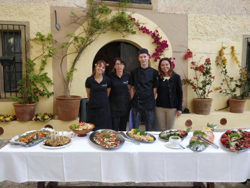 a group of people standing around a table with food at Finca Hotel Rural Predio Son Serra in Can Picafort