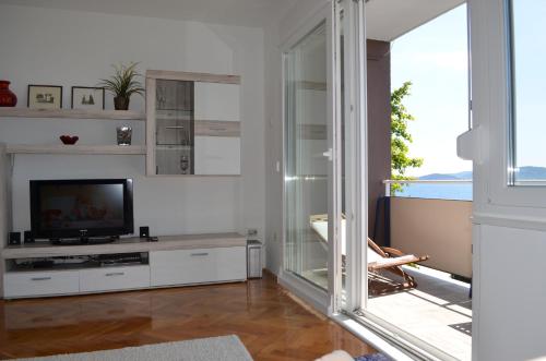 ein Wohnzimmer mit Fernseher und Glasschiebetür in der Unterkunft Apartment Roxy in Zadar