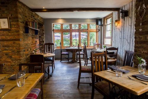 a restaurant with wooden tables and chairs and a brick wall at Mount Edgcumbe in Royal Tunbridge Wells