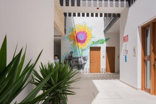 a mural on a wall in a hallway with a plant at La Mina Hostal Boutique in Conil de la Frontera