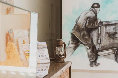 una pintura de un hombre parado en un mostrador con una lámpara en La Mina Hostal Boutique, en Conil de la Frontera