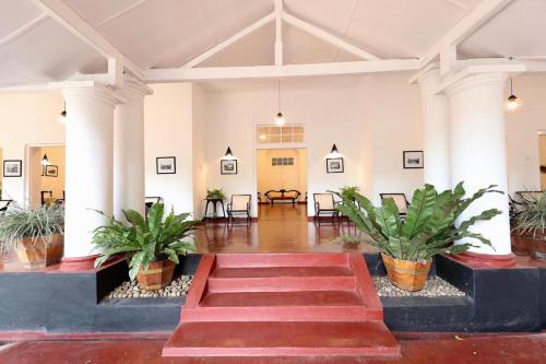 a lobby with a staircase and potted plants at Heritage Belihuloya Resort in Belihul Oya