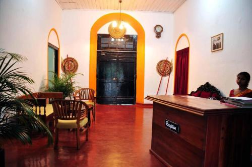 a man sitting at a desk in a room with a table and chairs at Heritage Belihuloya Resort in Belihul Oya
