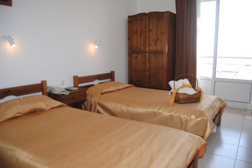 a hotel room with two beds and a basket on the seat at Maria Rooms in Agia Ermioni