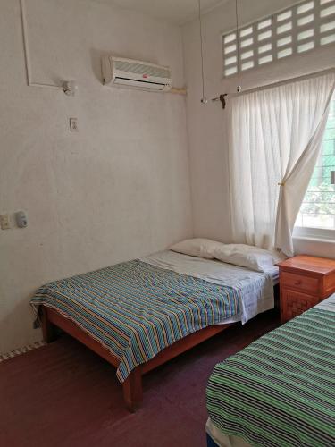 a small bedroom with two beds and a window at Casa Lao Centro in Zihuatanejo